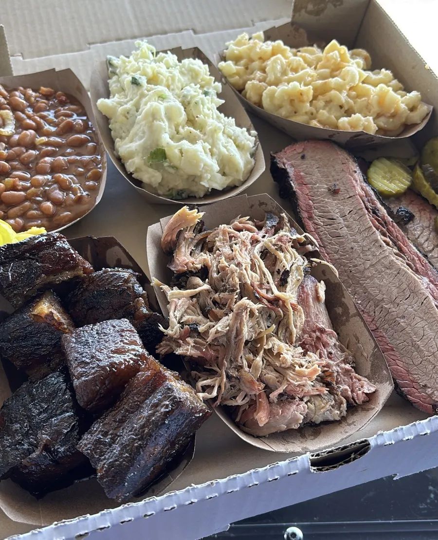 Boxed catering tray with pork belly burnt ends, pulled pork, brisket, and sides